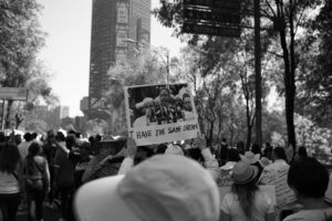 A monochrome image capturing a multitude of individuals raising signs, showcasing and projecting to save dreams and innovation amidst the crowd.