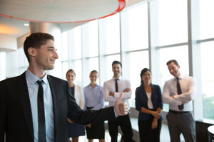 a-man-in-a-suit-giving-a-thumbs-up-gesture-with-people- in-the-background