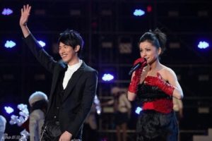 Alice Basco’s singing on stage and standing next to a man - Journey in The Entertainment Industry