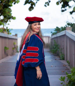 A girl standing and wearing a graduation gown and cap.