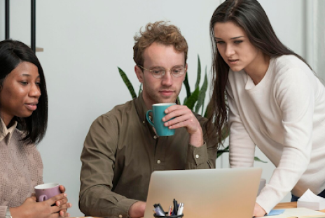 young-office-employees-discussing-work-in-front-of-a-laptop