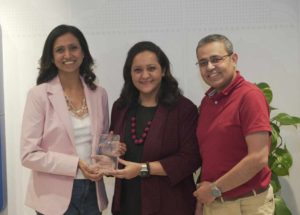 Pooja Gupta standing next to people and holding an award 