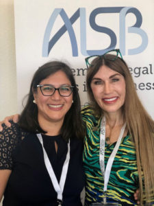 T. Leigh Anenson’s standing next to a women and smiling at the camera