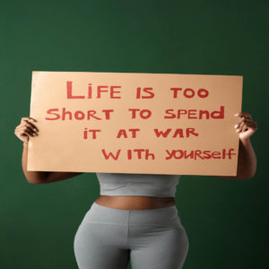 woman-holding-a-sign-saying-life-is-too-short-to-spend-it-at-war-with-yourself