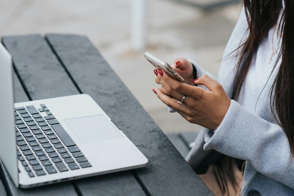 crop-ethnic-businesswoman-chatting-on-smartphone-near-laptop-on-table