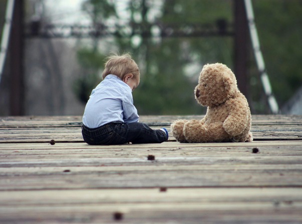 boy-sitting-with-brown-bear-plush-toy-on-selective-focus-photo