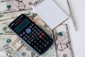 image of-a-calculator-and-notepad-placed-on-US-dollars-stack