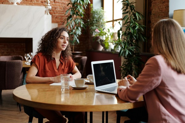 Two-businesswomen-engage-in-a-meeting-at-a-cozy-coffee-shop-discussing-work-on-a-laptop