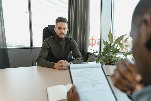 Professional-man-in-turtleneck-at-office-desk-during-an-interview