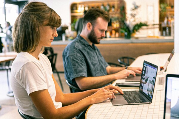 Two professionals working on laptops in an online outsourcing setting