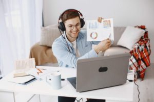 man-sitting-in-the- living-room-at-home-enjoying-studying-using-a-laptop-and-a-headset