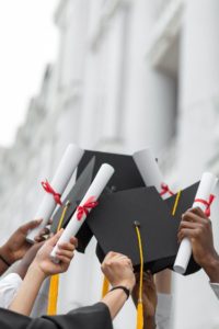 close-up-of -graduates-raising-their-caps-and-diplomas-in-celebration