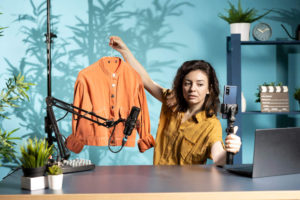 Woman-filming-fashion-vlog-holding-jacket-in-hand