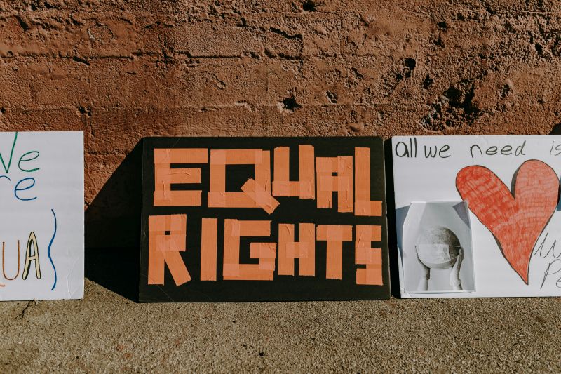 three placards about equal rights set up against a brick wall