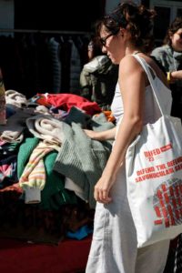 image of a women doing thrift shopping women searching for clothes in a thrift stall