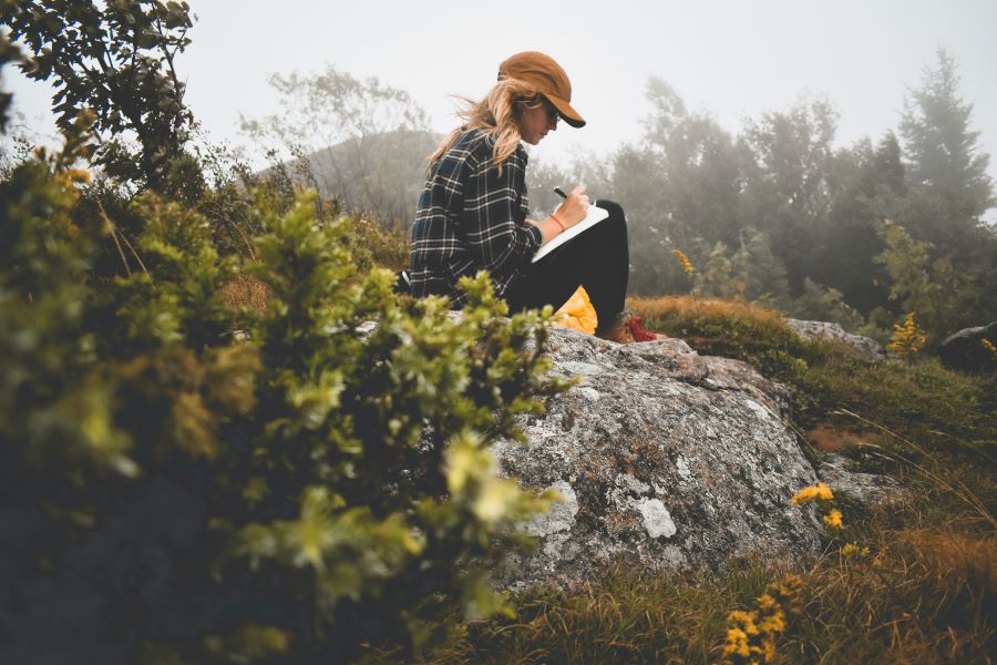 Girl journaling on a mountain