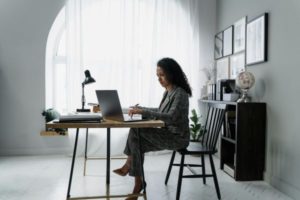 woman-in-gray-jacket-sitting-on-chair-using-laptop-computer