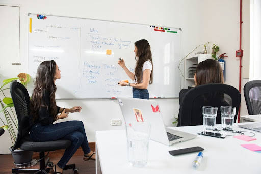A woman discussing something using a whiteboard with a team.