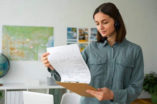 A woman wearing a headset and reading a paper.