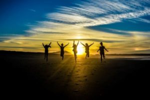 people-jumping-on-shore-front-of-golden-hour