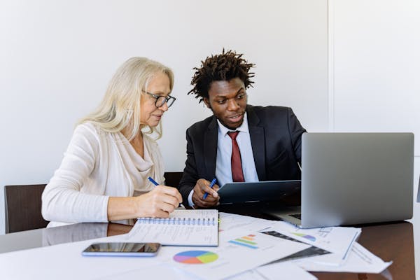 elderly-woman-looking-at-the-computer-beside-a-man-in-black-suit