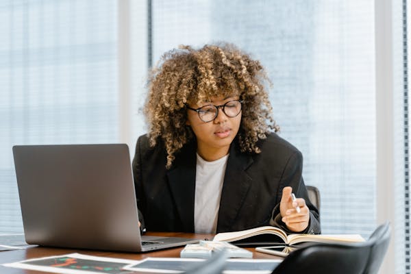 a-woman-in-black-blazer-sitting-near-the-table-with-laptop