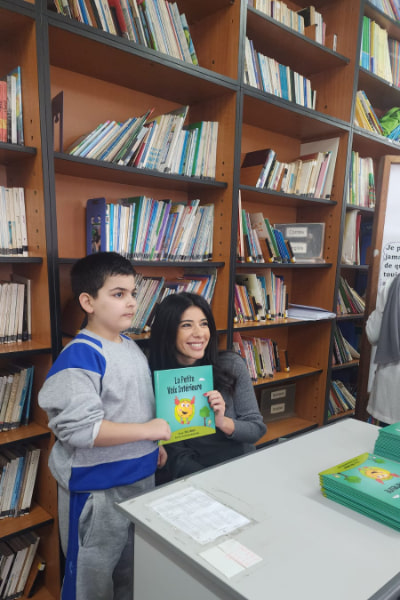 an-image-of-rhea-jabbour-smiling-while-giving-a-book-to-a-child