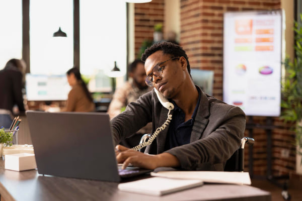 businessman-using-landline-and-laptop