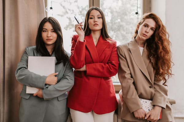 three-women-in-business-attire-standing-near-window
