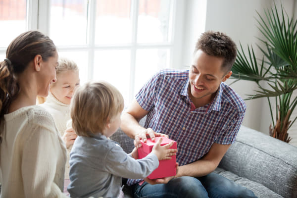 little-son-presenting-gift-dad-family-celebrating-fathers-day