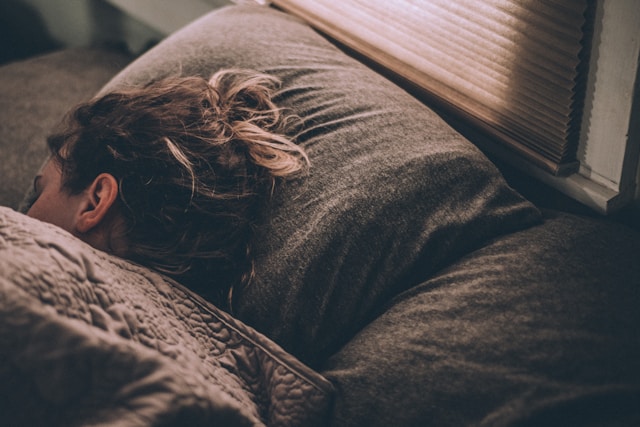 woman-sleeping-on-bed-under-blankets