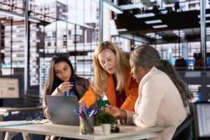 Women collaborating in an office meeting, discussing ideas and overcoming the confidence gap in the workplace.