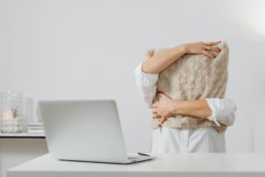 Embarrassed woman shields herself from her laptop symbolizing online anxiety.
