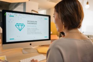 Woman reviewing a digital personal brand profile on desktop.