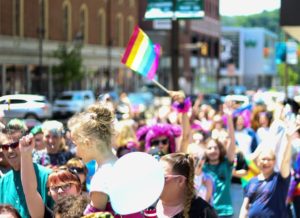 A crowd celebrating Pride with rainbow flags, representing how pink capitalism has turned LGBTQ+ visibility into a seasonal marketing moment.