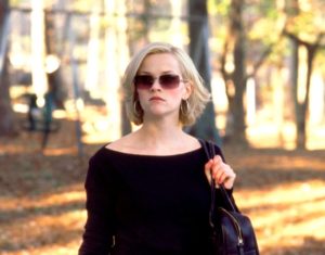 Blonde woman wearing sunglasses and carrying a bag outdoors in a scene from Sweet Home Alabama.
