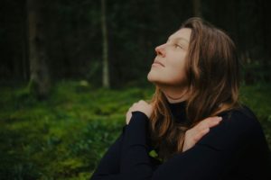 woman-sitting-with-hands-crossed-in-the-forest
