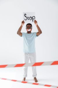 A man holding a “Stop” sign while standing behind red-and-white barrier tape.