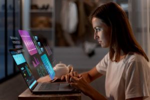 A businesswoman analyzing data visualization charts floating above her laptop screen.