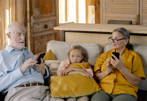 A child sitting with grandparents but looks sad