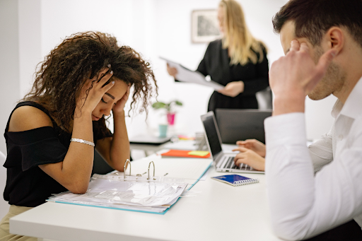 Stress-at-work-woman-holding-her-head-sitting-across-a-man-at-the-table