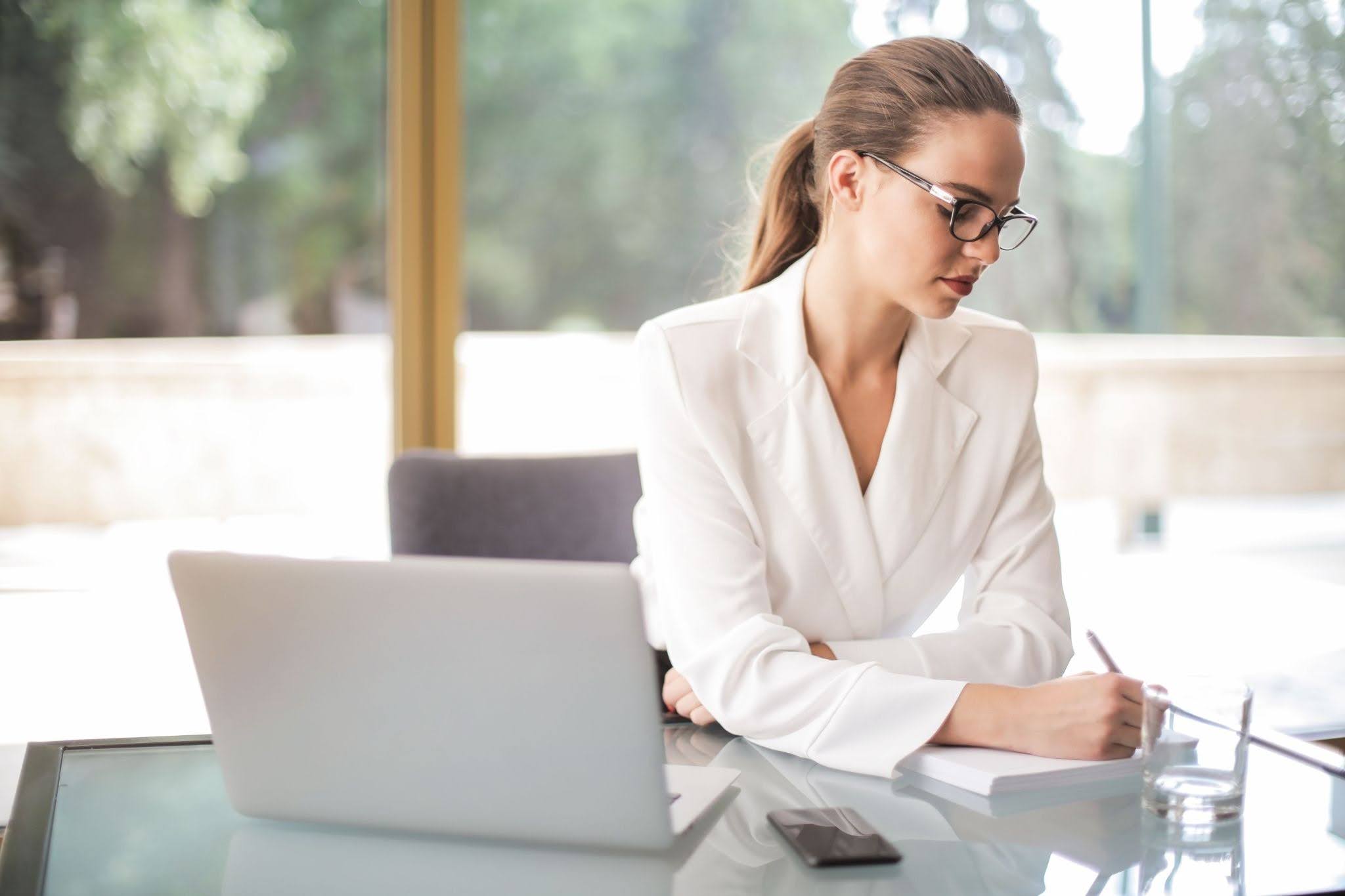 A confident woman reviewing documents at her desk, representing how women are taking control of their careers and actively seeking employers committed to workplace equity and inclusion.