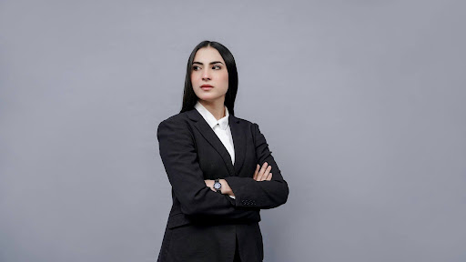  A professional woman sitting at a desk looking thoughtfully at her laptop, representing the growing number of women reconsidering career advancement in today’s workplace. 