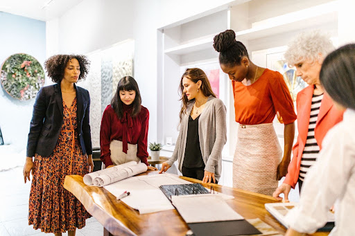 A diverse group of women in a professional setting, illustrating how structural barriers at early career stages limit women’s access to promotion and leadership development opportunities.